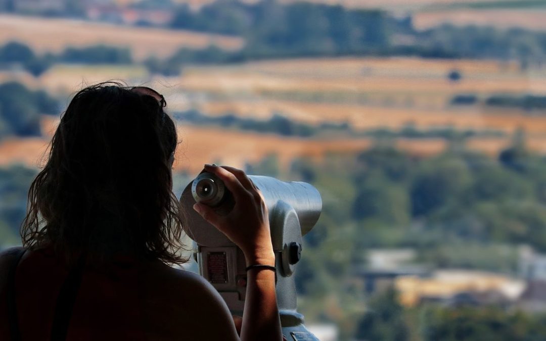 woman looking through view finder over landscape