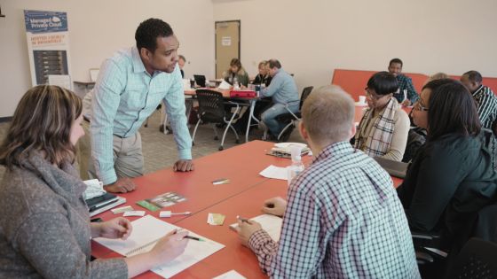 business coach speaking to a table full of entrepreneurs